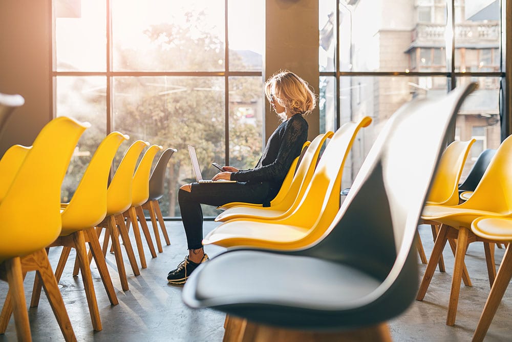 young pretty woman sitting alone in co-working office, conference room, working at laptop